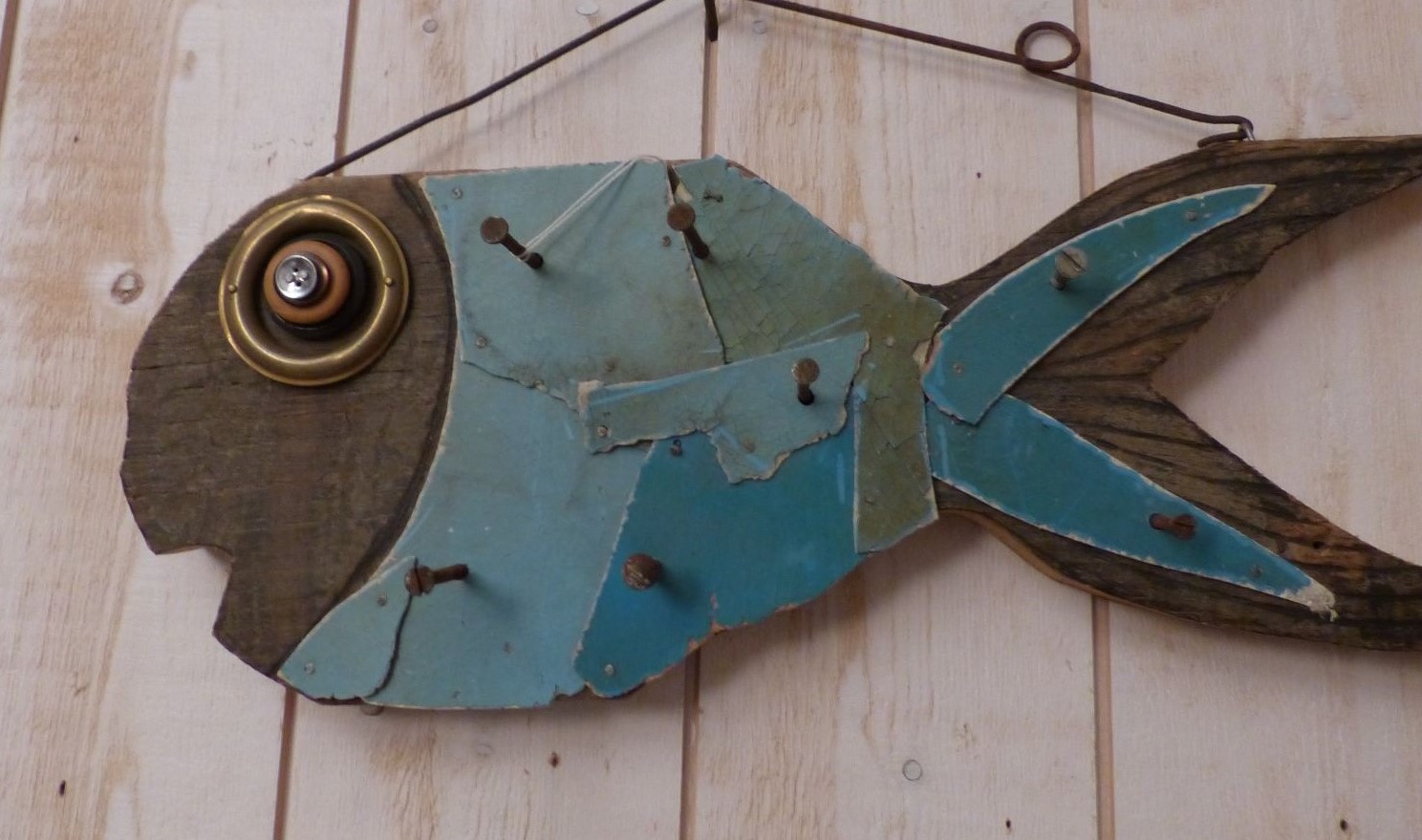Poisson bleu sculté dans du bois flotté accroché au mur